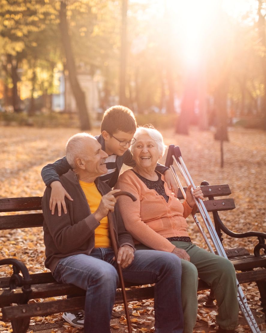 Older couple seated on a bench with their grandchild.