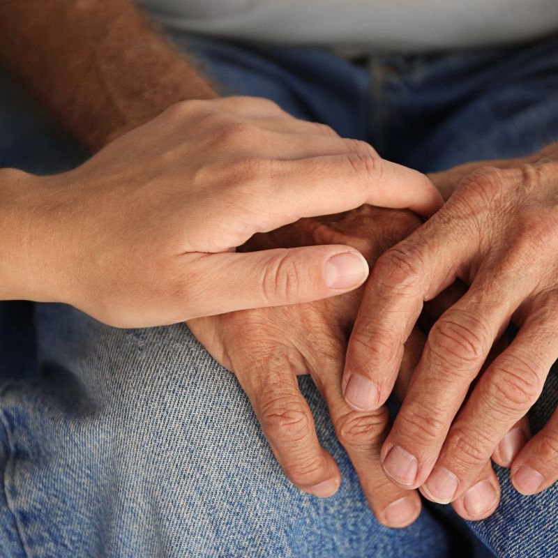 Younger woman holding older adult's hands.